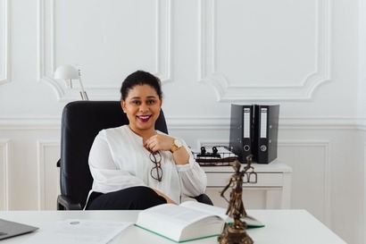 A confident attorney sitting at her desk with legal books and the Lady Justice statue, reflecting the range of careers available to those exploring what you can do with an LLM degree.
